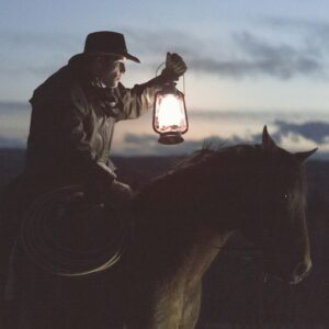 Man with a lantern riding a horse in the past