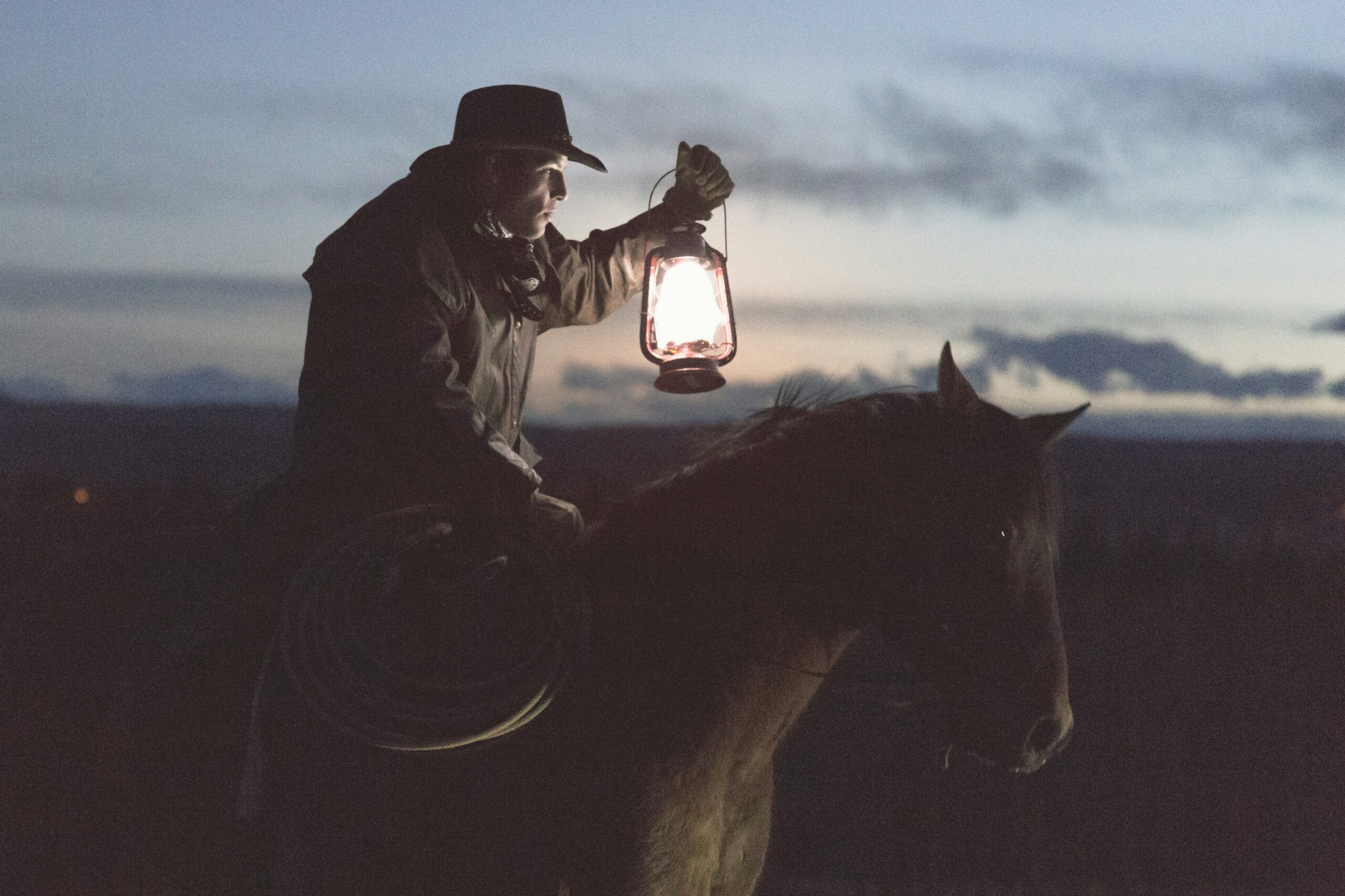 Man with a lantern riding a horse in the past